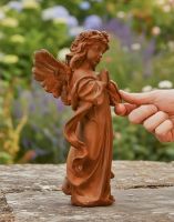 Digital illustration of Rustic Cast Iron Winged Praying Angel Sculpture with hand in shot for scale
