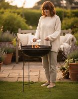Digital Illustration of the "Annapurna" Wrought Iron Indian Kadai Bowl & Fire Pit with a Lady Stood Cooking with it in a Garden