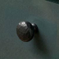Digital Illustration of the 33mm Black Hammered Steel Cabinet Knob Mounted on a Blue Cupboard Door