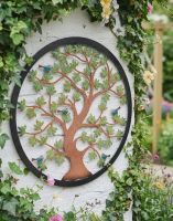 Digital Illustration of the 60cm Version of the Multi-Coloured Circular "Tree of Life" Garden Wall Art on the Corner of a White Garden Wall Covered in Ivy