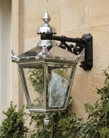 Digital Illustration of the 63 x 47.5cm Version of the Bright Chrome Suspended Wall Lantern Mounted on the Side of a Sandstone Building