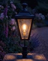 Digital Illustration of the 71cm Black Dorchester Pillar Light and Lantern Set Mounted on a Stone Garden Pillar Surrounded by Flowers Viewed Face on and Lit up at Night