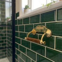 Digital Illustration of the Brass Period “Classic” Toilet Roll Holder Empty on Green Bathroom Tiles from an Angled View