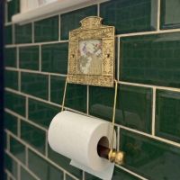 Digital Illustration of the Brass Version of the Globe Toilet Fixture Holding Toilet Roll Mounted on Green Bathroom Tiles