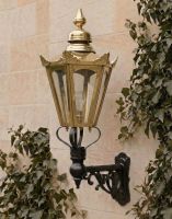 Digital Illustration of the Medium Concordia Hexagonal Brass Lantern On a Capella Bracket Lit up at Night Mounted on a light Coloured Sandstone Brick Wall