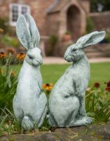 Digital Illustration of Verdant Watchers Pair of Sitting Rabbit Garden Sculpture Cast Aluminium in Front of a Countryside Cottage