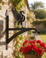Digital representation of Liver Bird Iron Hanging Basket Bracket mounted on a cottage