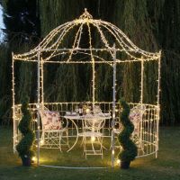 Digital representation of "The Countess" Gazebo with fairy lights at night and table and chair set in centre