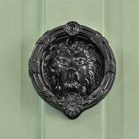 Traditional Sandringham black lion door knocker on pastel green door Traditional Sandringham black lion door knocker on pastel green door