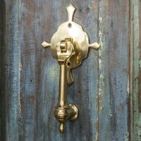 Polished Brass Turnbrook Park door knocker on Old Wooden Door Polished Brass Turnbrook Park door knocker on Old Wooden Door