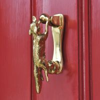 Polished Brass Running Fox Door knocker on red door Polished Brass Running Fox Door knocker on red door