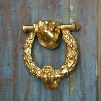 Polished Brass Fist & Laurel door knocker on blue rustic door Polished Brass Fist & Laurel door knocker on blue rustic door