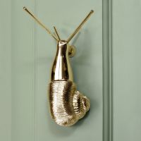 Polished brass Snail door knocker on pastel green door