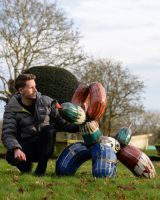 ‘Tangle’ the Balloon Dog Upcycled Oil Drum Garden Sculpture with man crouched down next to sculpture for scale