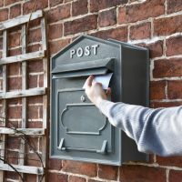 Grey Wall Mounted Post Box with Lettering Being Posted 