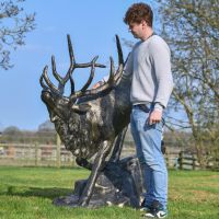 Male stood next to Elk on Rock Sculpture for scale 