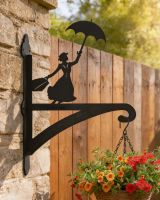 Digital representation of Flying Nanny Iron Hanging Basket Bracket mounted on brick wall with fence in background