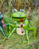 Close up of light green frog garden sculpture