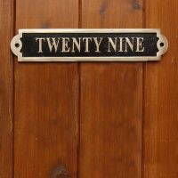 The Number Twenty Nine Displayed on the Black & Brass Gate Number Sign on a Wooden Door
