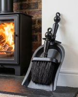 The "Duchess" Black Iron Shovel and Brush Set next to some Logs ready for use in a Log Burner Stove - Digital Illustration