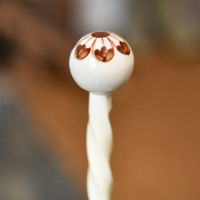 Close up image of ceramic cream & brown finial