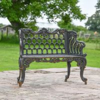 Aged Black Ornate Garden Bench in Garden Setting  Aged Black Ornate Garden Bench in Garden Setting