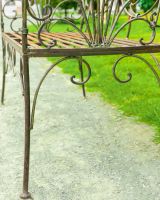 Close up of ornate leg detail on rustic iron garden bench