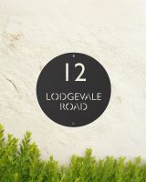 Black Modern Circular Design Steel House Sign Mounted on the Front of a House