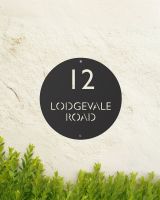 Black Modern Circular Design Steel House Sign Mounted on the Front of a House Black Modern Circular Design Steel House Sign Mounted on the Front of a House