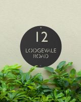 Modern Circular Steel House Sign Mounted onto a Painted House Wall Modern Circular Steel House Sign Mounted onto a Painted House Wall