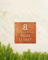 Modern Square Corten Steel House Number Sign on a Rustic Cream Wall