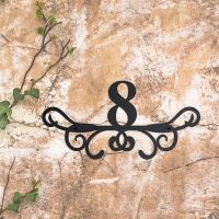 Ornate Scroll Iron House Number Sign on a Rustic Wall