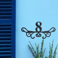 Ornate Scroll Iron House Number Sign on a Blue Wall