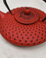Close-Up of Black Dotted Pattern on Red Cast Iron Teapot