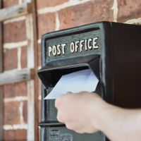 Letter Being Deposited into Black Newland Post Box 