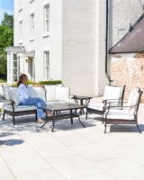 Wide shot of the full "Elmswood" Outdoor Furniture Set with person sat on sofa showing scale.