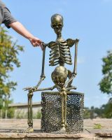 Scale image of gold skulls and skeletons outdoor statue
