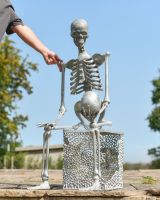 Scale image of skeleton holding skull outdoor statue