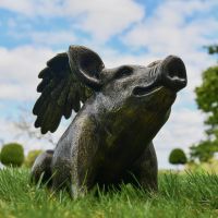 Brushed Gold Flying Pig Sculpture in Garden Setting  Brushed Gold Flying Pig Sculpture in Garden Setting