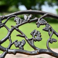 Close up of aged black cast iron branch detailing on garden bench