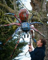 Tarantula Upcycled Oil Drum Garden Sculpture hanging from a tree with terrified man below to reference scale