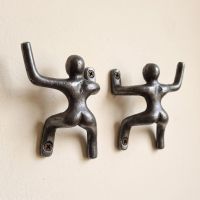 The 100mm Climbing Man Cast Antique Iron Coat Hook Pair Shown on a Magnolia Coloured Interior Wall - Digital Illustration