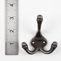 The 1883 Victorian Triple Prong Cast Iron Coat Hook on a White Background next to a Steel Ruler for Scale - Digital Illustration