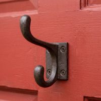 The 90mm Compact Cotswold Antique Iron Coat Hook Shown up Close on a Red Door - Digital Illustration