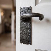 The Aldrington Cast Iron Door Handle Shown Close up Mounted on a Grey Door in a Modern Interior - Digital Illustration