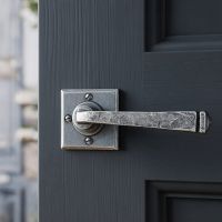 The Arya Unsprung Pewter Iron Door Handle Set On a Grey Door in a Modern Door - Digital Illustration