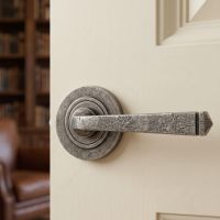 The Ayre Gardens Aged Pewter Unsprung Lever Door Handle on Rose Shown up Close on a Cream Door - Digital Illustration