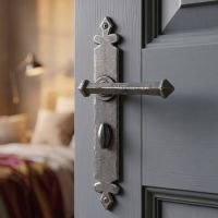 The Azzaro Medieval Style Pewter Lever Handles With Bathroom Lock Pair Shown on a Bedroom Door in a Modern Home - Digital Illustration
