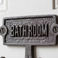 The Bathroom Plaque Double Robe Hook in Cast Antique Iron Showing a Close up of the Text - Digital Illustration