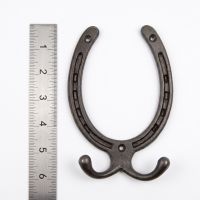 The Blacksmith Vintage Cast Iron Horseshoe Robe Hook next to a Ruler On a White Background  - Digital Illustration